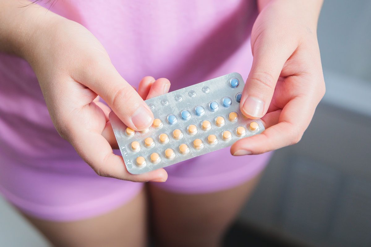 Woman Wearing Pink Pajama Holding Birth Control Pills